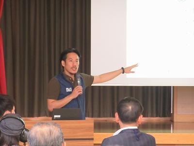 講師が手をスクリーンに指して、話している写真