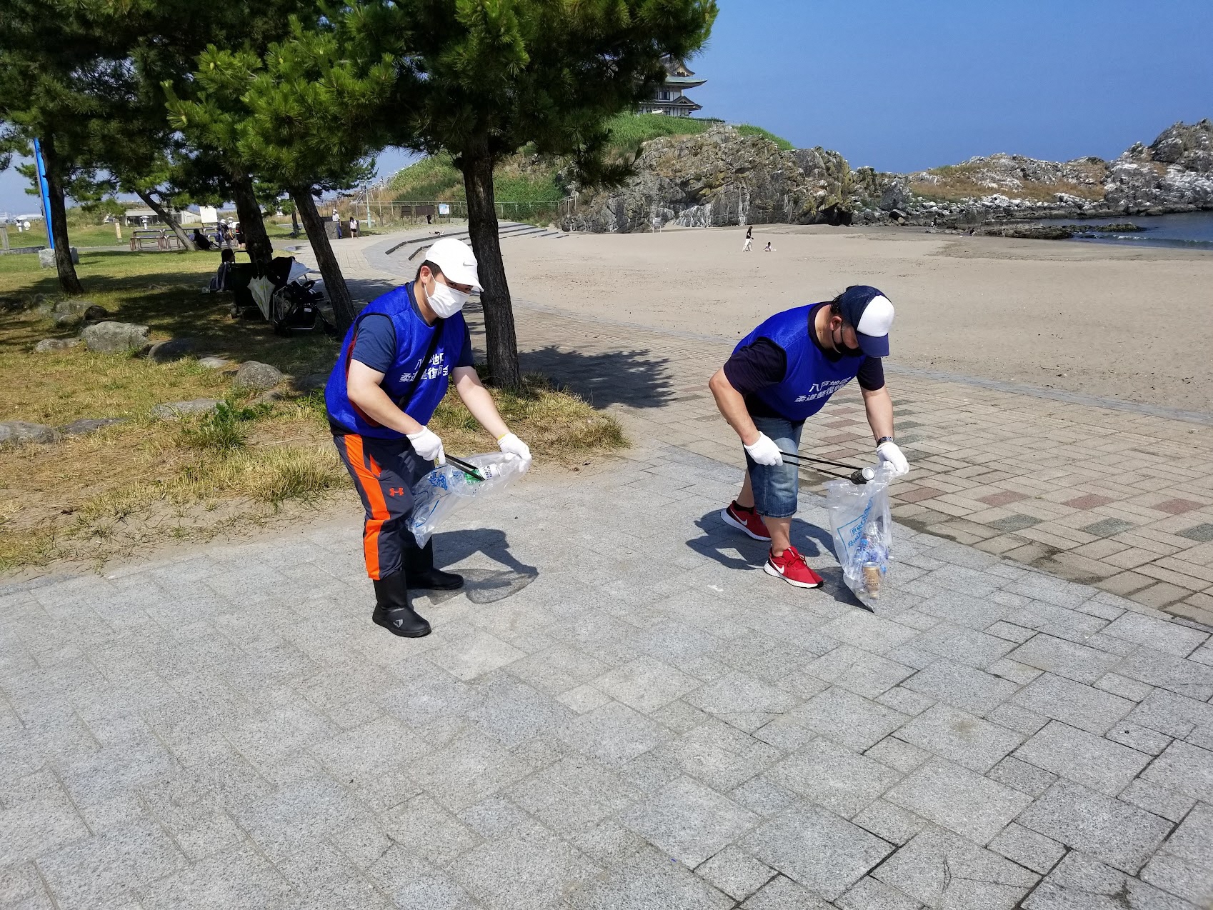 蕪嶋神社をバックにトングでごみひろい