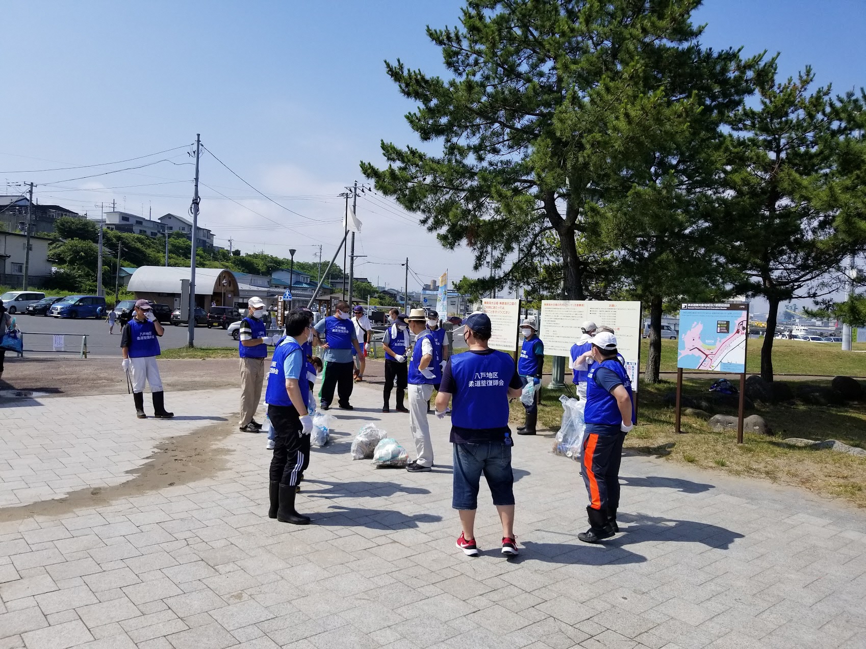 蕪島の案内看板の前で集めたごみを中央に置き話し合う様子