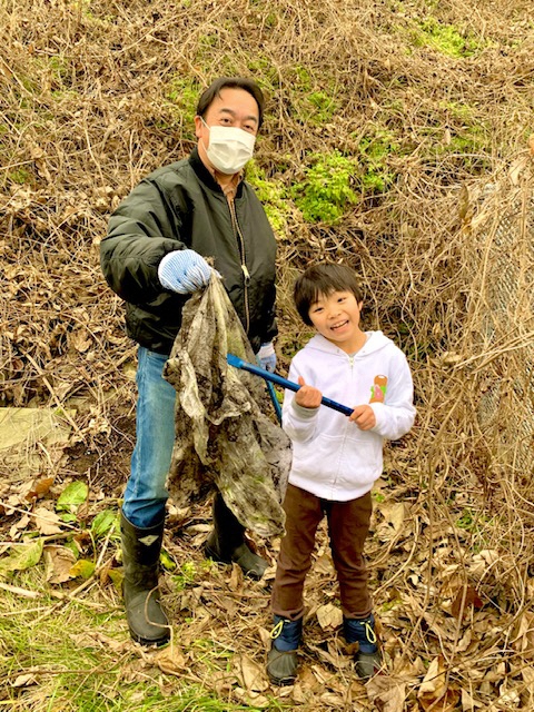 トングを持った男の子とビニール袋を拾う男性の写真