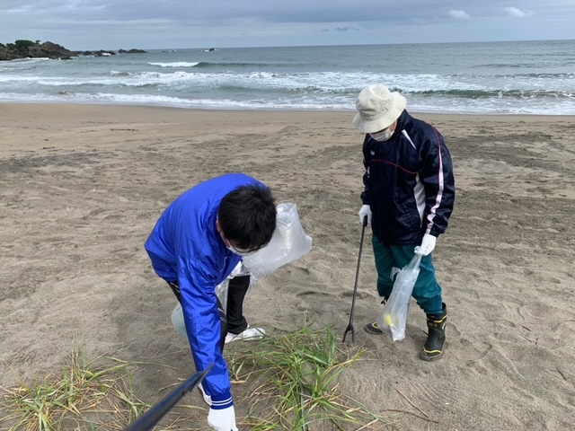砂浜のごみを拾っている写真