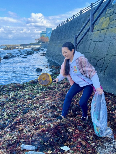 波打ち際ギリギリで漂着ごみを拾っている写真