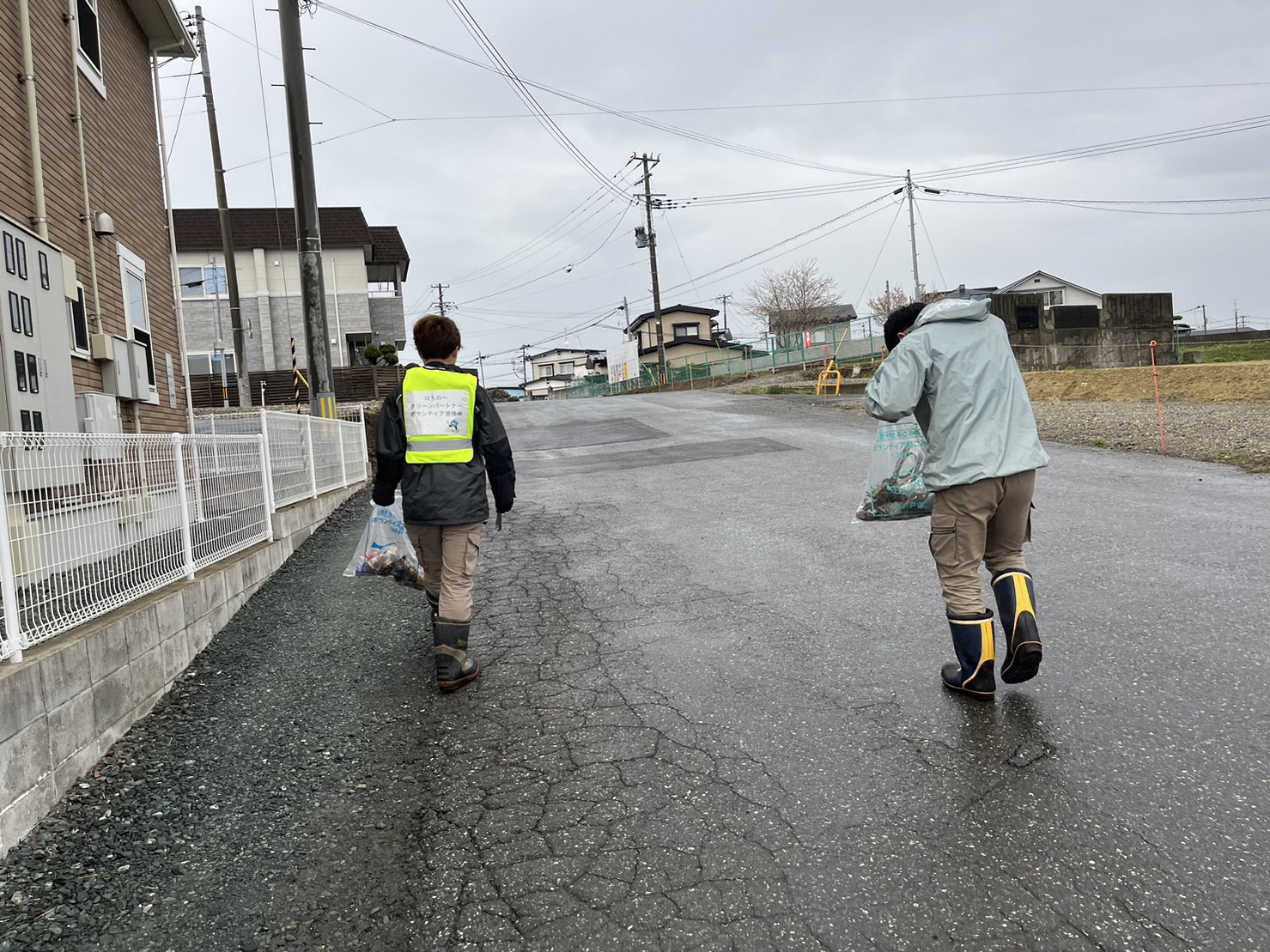 住宅地のごみがないかトングを持ち歩いている2名の写真