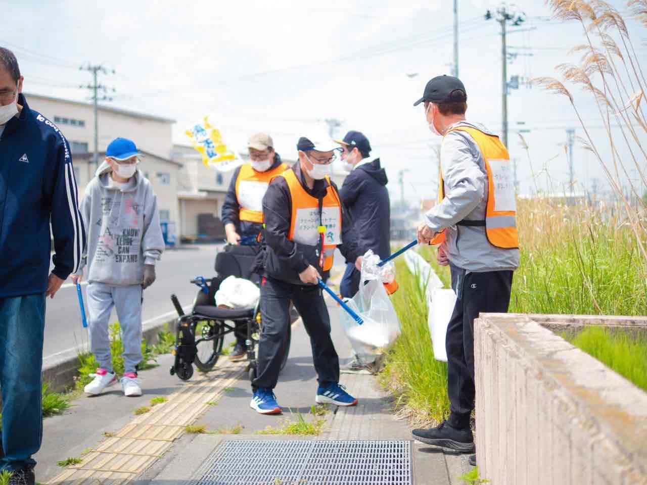数名で歩道のごみを拾っている写真