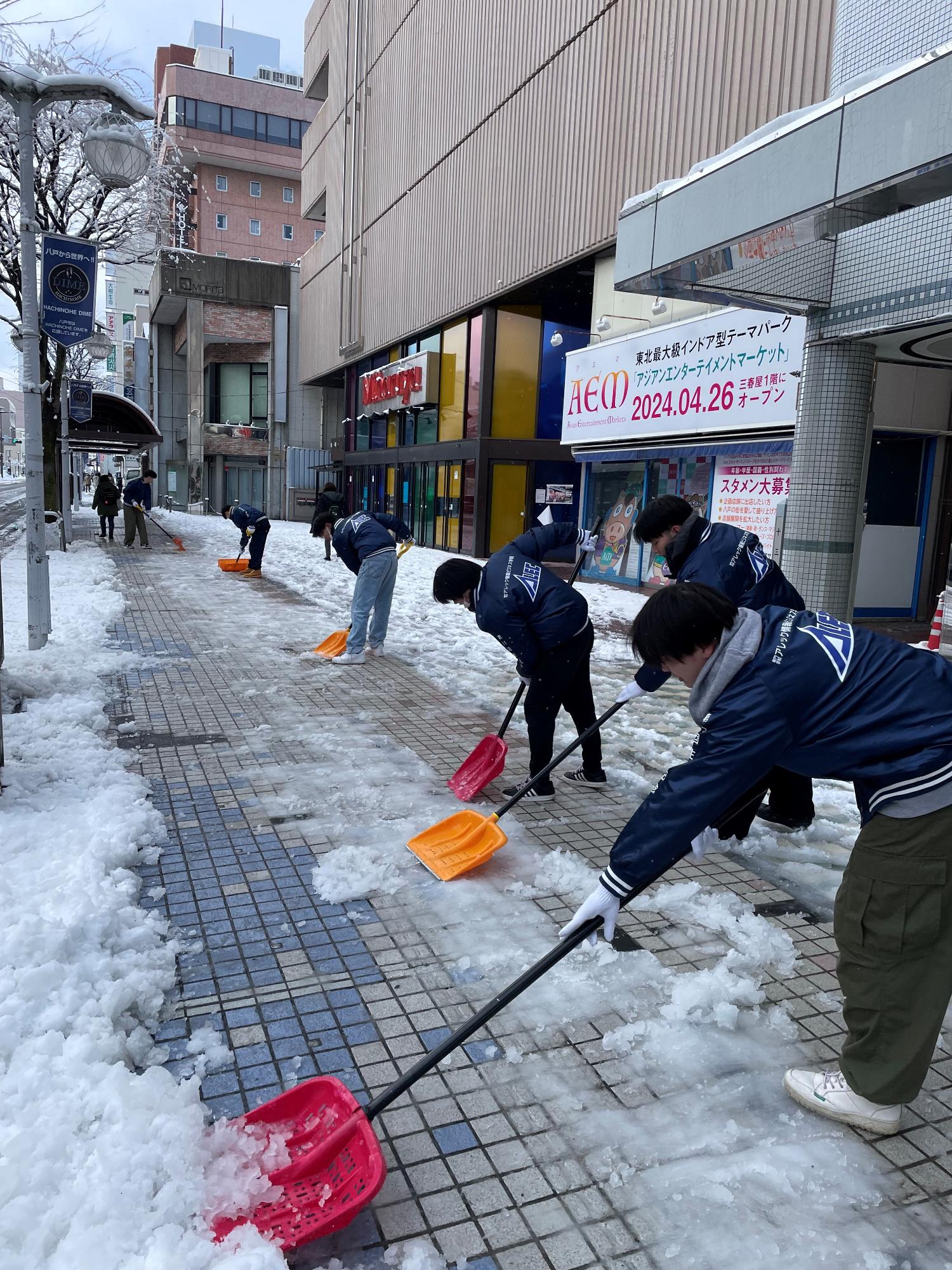 旧三春屋まえの歩道の除雪をする生徒さんたち
