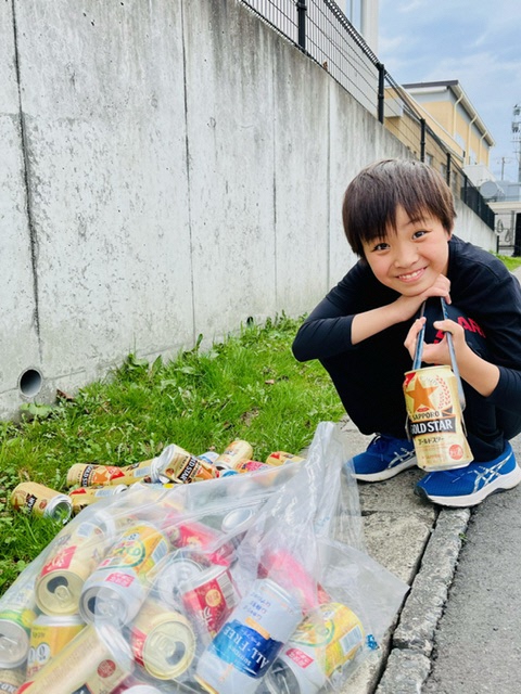 拾い集めた大量の空き缶と男児の写真