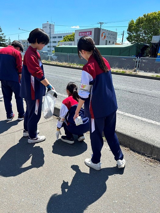 歩道のごみを拾っている生徒たちの写真