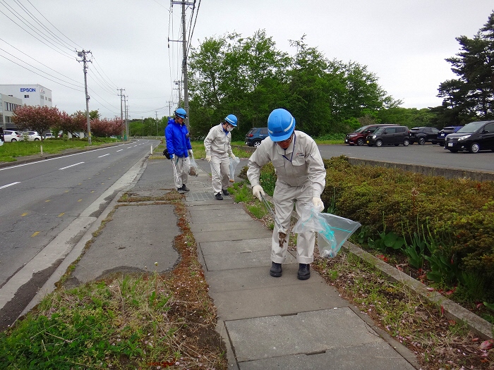 作業服で歩道のごみを拾っている写真