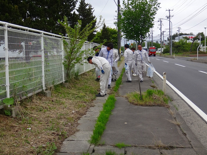 歩道のごみを拾う作業服の人の写真