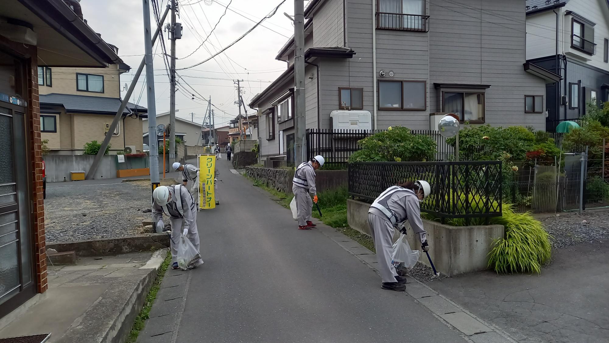 住宅地の道路のごみを拾っている写真