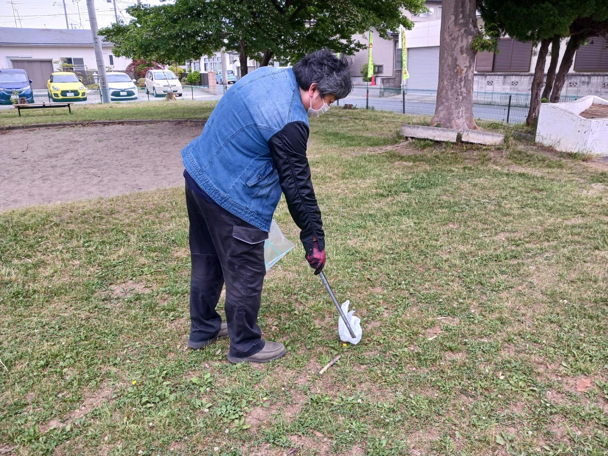 トングでゴミを拾っている人の写真