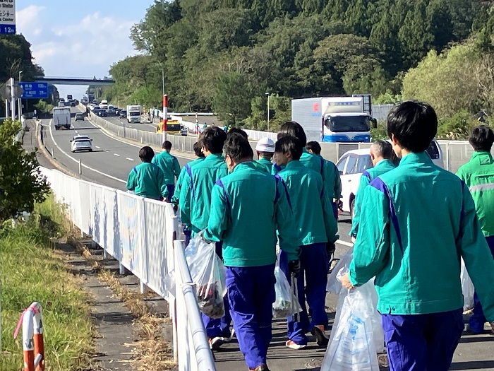 青空の中、北インターバイパスの歩道を作業服で歩いている参加者の皆さんの写真