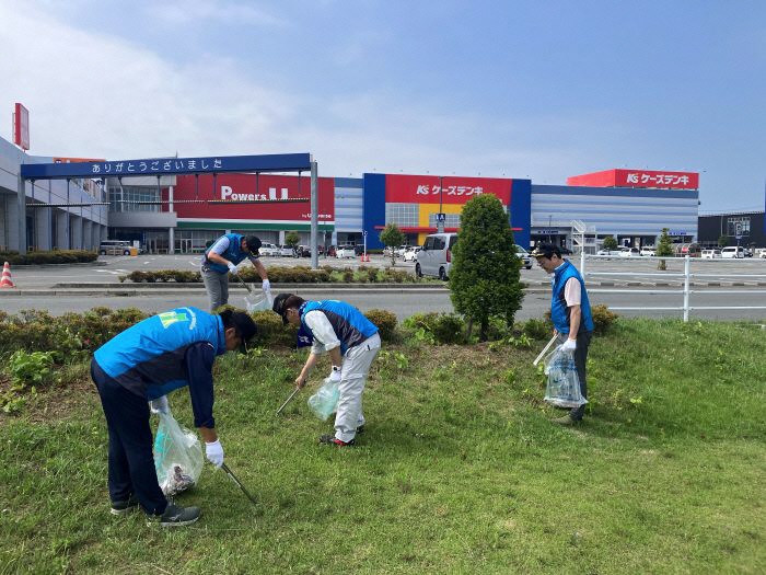 道路脇の草地のごみを拾う写真