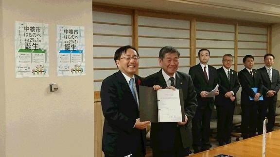 署名後の引継書を披露する三村伸吾青森県知事と小林眞八戸市長の写真
