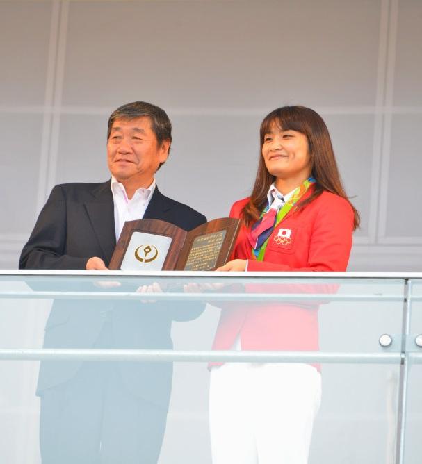 市民特別栄誉大賞の盾を持ち伊調 馨選手と市長が笑顔で記念撮影をしている写真