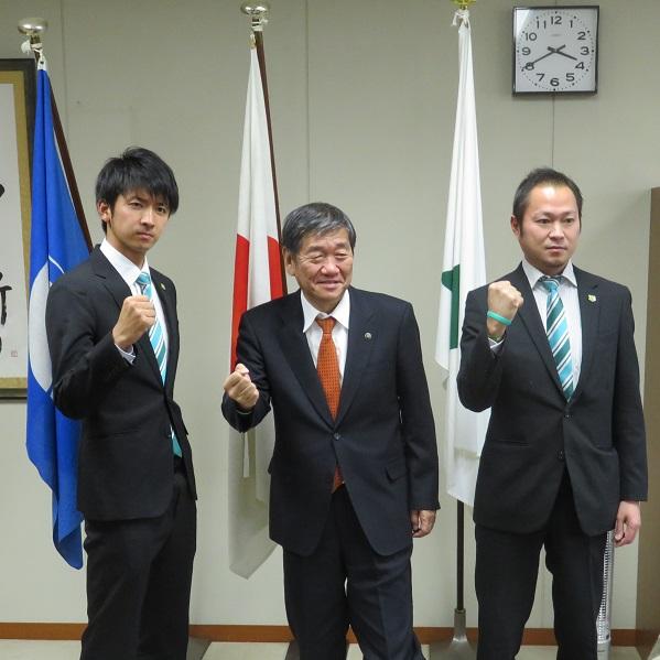 ヴァンラーレ八戸の細越健太郎代表と須藤主将とガッツポーズで記念撮影をしている市長の写真