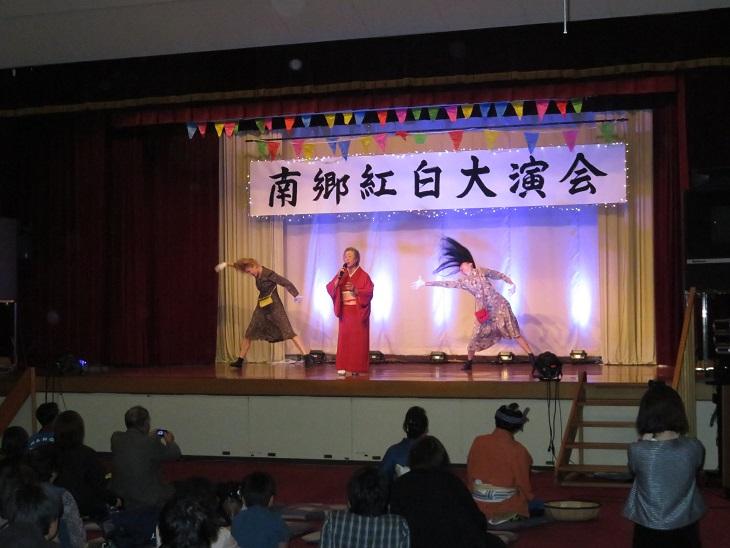 「南郷紅白大演会」で着物を着た高齢の女性が歌い後ろでワンピースを着て女装をした2名がダンスをしている写真