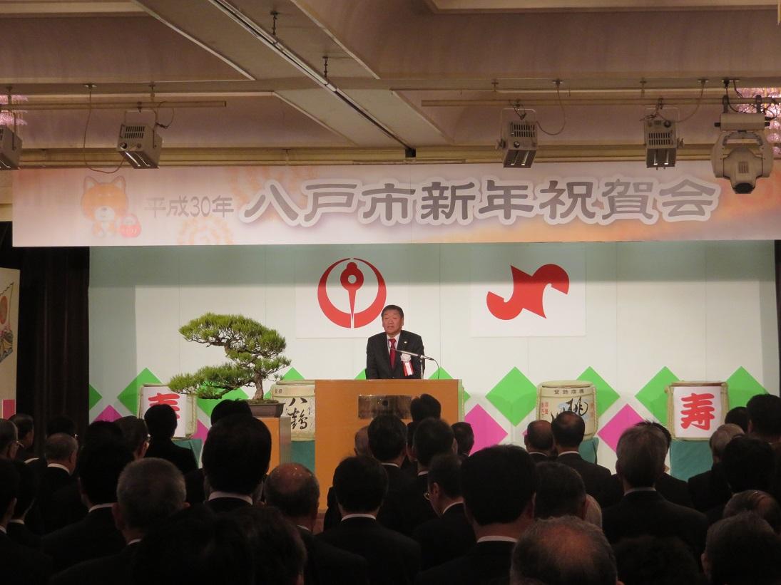 八戸市新年祝賀会会場で出席者を前に挨拶をしている市長の写真