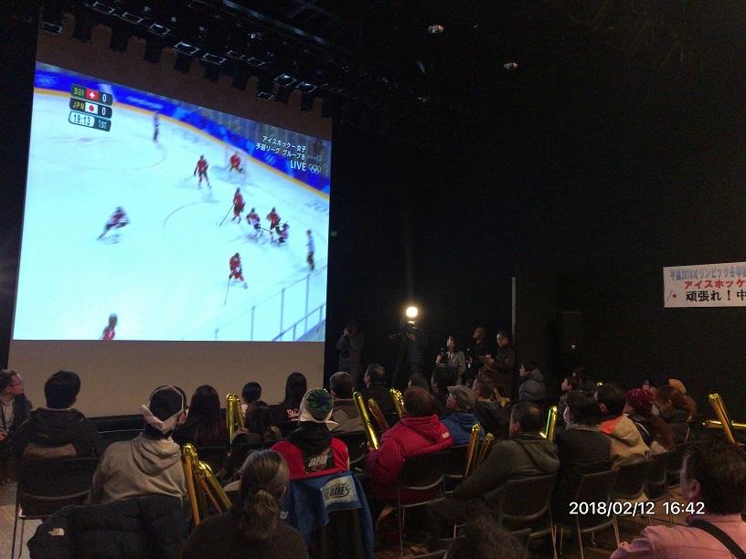 八戸ポータルミュージアムはっちで大スクリーンに映し出されたアイスホッケーの試合を観戦している市民の皆さんの写真