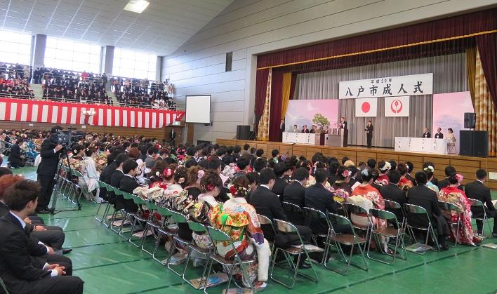 八戸市成人式に集まった多数の新成人の皆様の前でステージ上に立ち挨拶をしている市長の写真