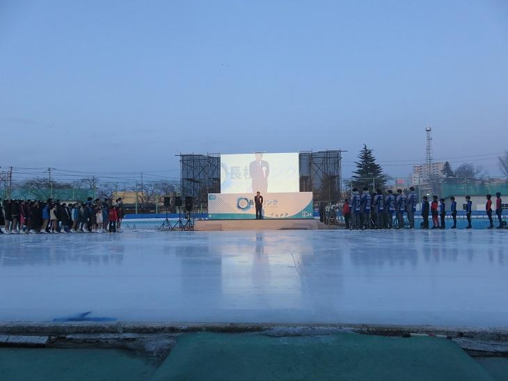 長根リンククロージングイベントでスケートリンクの前に作られた特設の舞台の左右には選手や参加者が集まり壇上で挨拶をしている市長の話しを聞いている写真