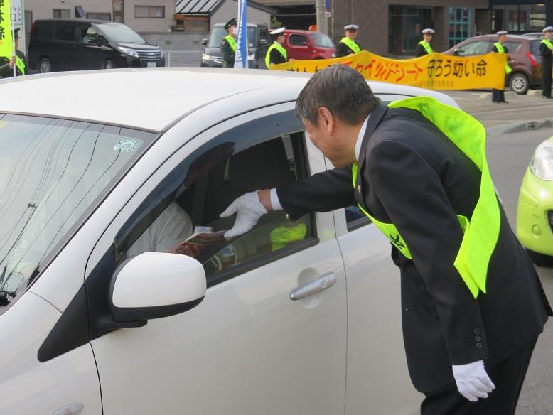広報チラシを運転者に渡して交通安全の呼びかけをしている市長の写真