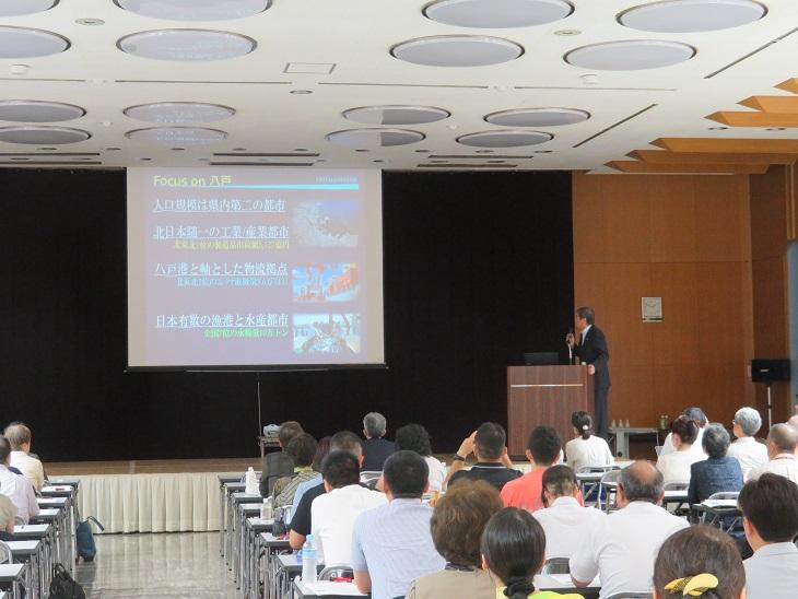 青函広域観光おもてなし人材育成研修会でスクリーンを使って講演をしている市長の写真