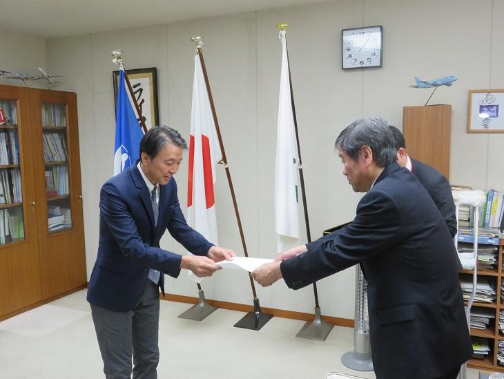 八戸市海外経済協力員に主任した工藤浩成（ひろまさ）様に委嘱状を交付している市長の写真
