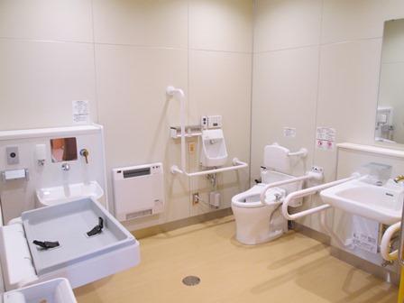 トイレや手洗い場に手すりがついてあり、ベビーベッドも設置されている広々とした多目的トイレ室内の写真