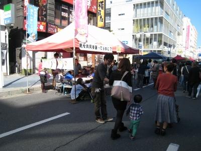 八戸市中心街にて設置したテントの前で親子に粗品を渡している様子の写真