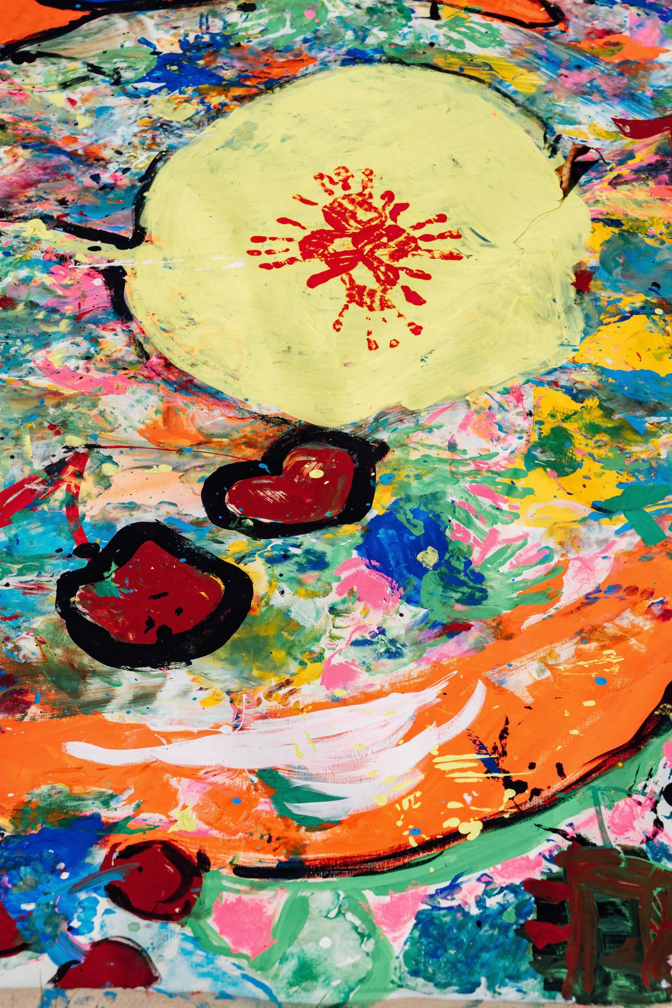 色とりどりの絵具で描かれたアート。明るい黄色の円に赤い印があり、周囲には多様な色合いの筆跡があ広がっている。