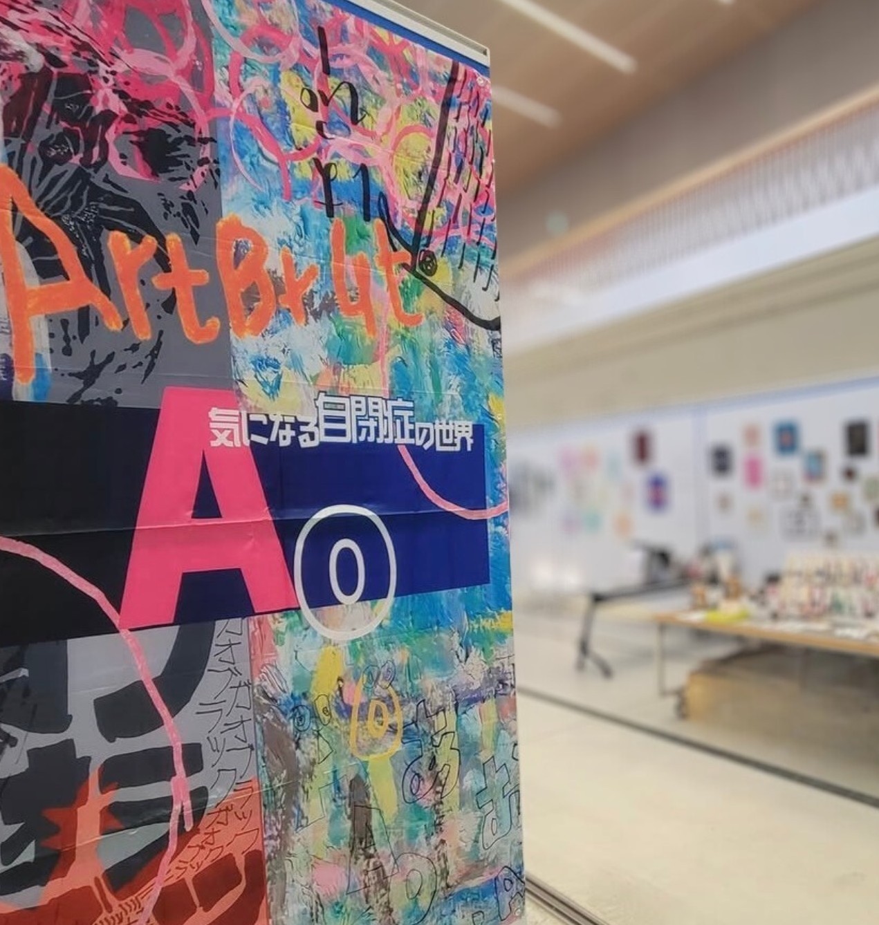 作品展のカラフルな横断幕。背景に鮮やかなアートが描かれており、展示会の一部が見える。