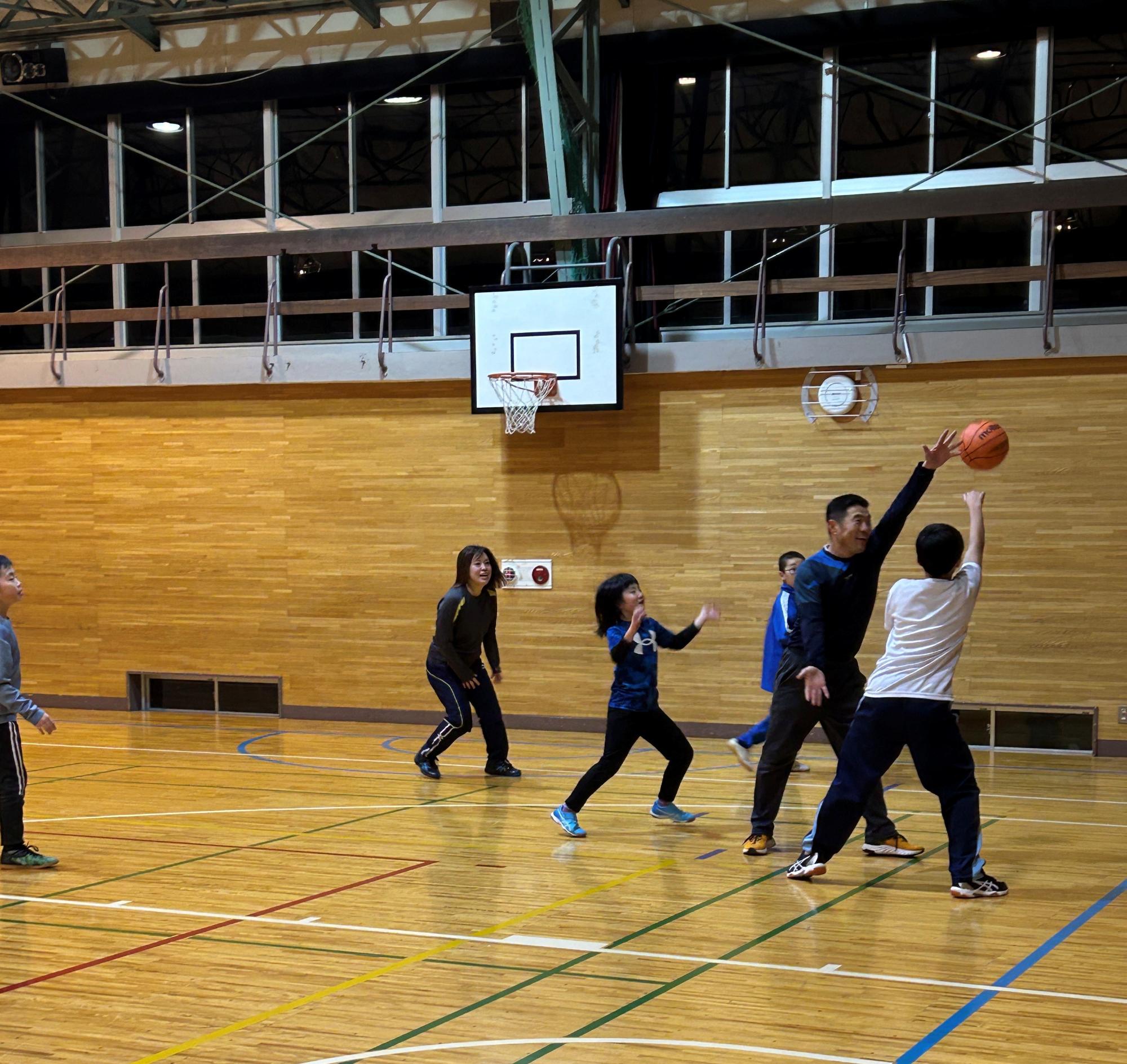 バスケットボールの試合中の子どもたち。選手がボールを投げる姿が写っている。