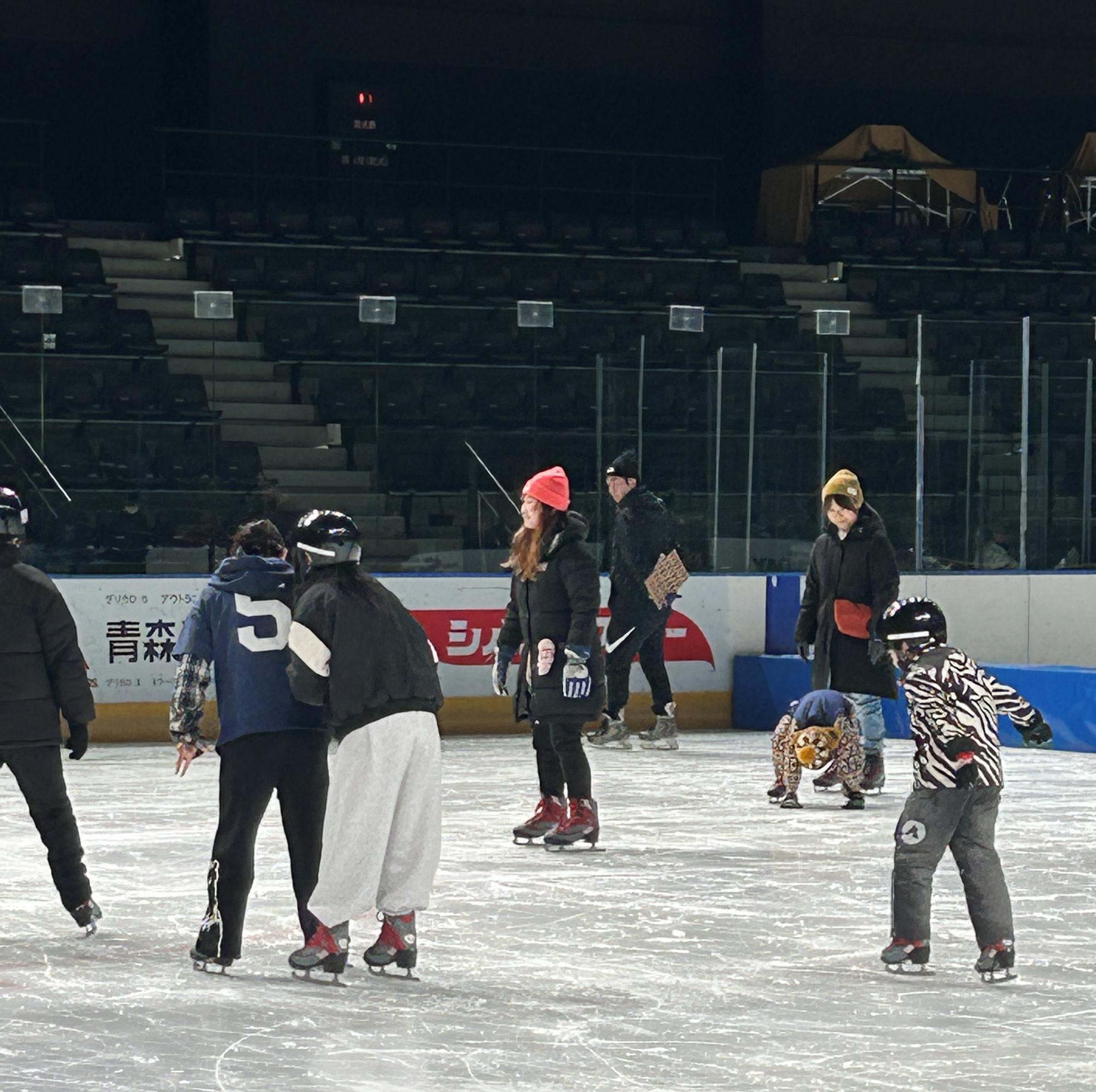 スケートリンクで楽しむ人々。複数の子どもや大人がアイススケートをしており、楽しそうな雰囲気が漂っている。