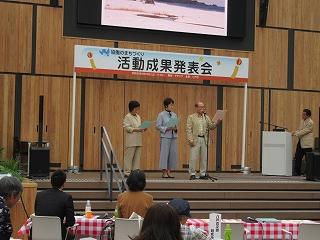 男性三人がステージ上で郷土の詩人の詩を朗読している写真