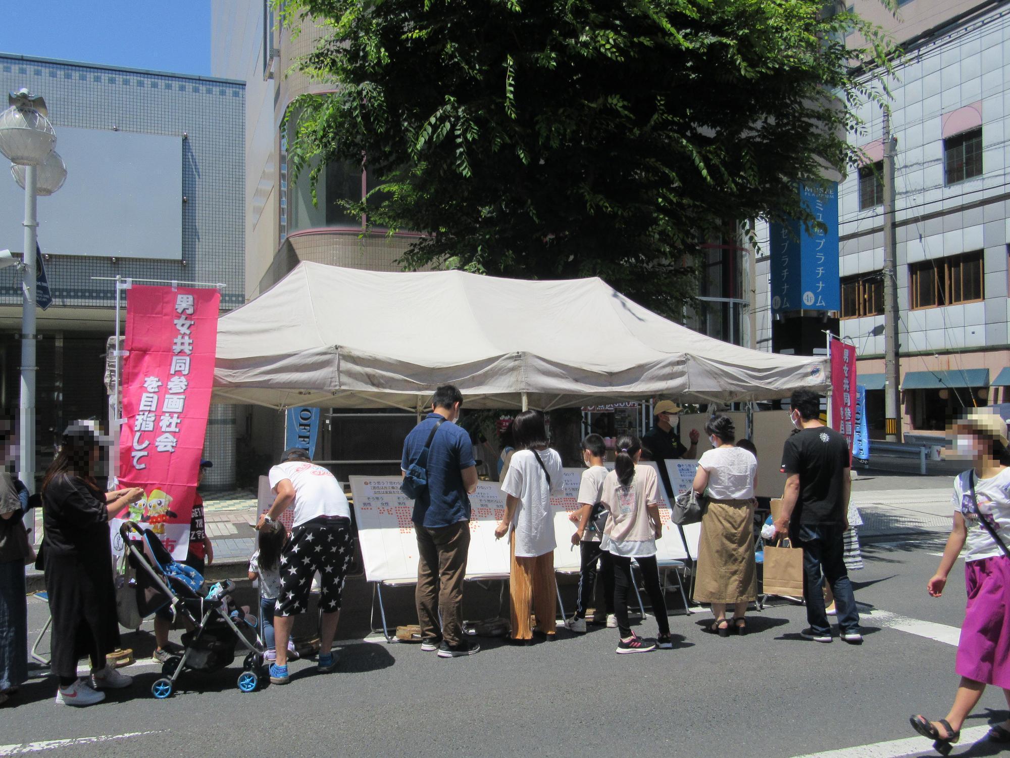 令和4年6月はちのへホコテンに出展した男女共同参画ブースのパネルアンケートに参加する人々の写真