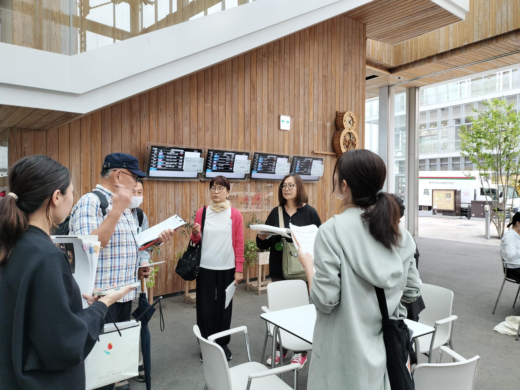 マチニワの公共スペースで資料を手に模擬ツアーを行う参加者たち