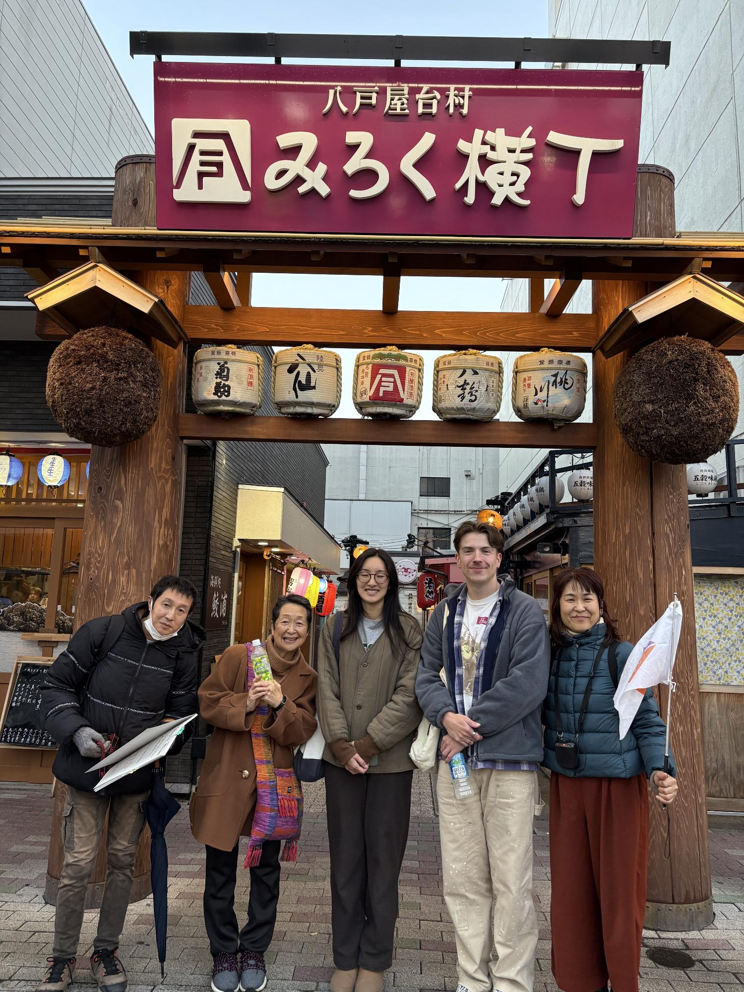 みろく横丁の入口前で並ぶ5人の集合写真