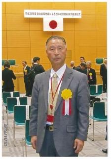 メダルをかけて記念撮影をする北山博秋氏の写真