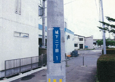 電柱に取り付けられた町名と街区符号を表示した街区表示板の写真