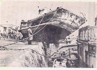 大きな船が損傷し半分が港に乗り上げている写真