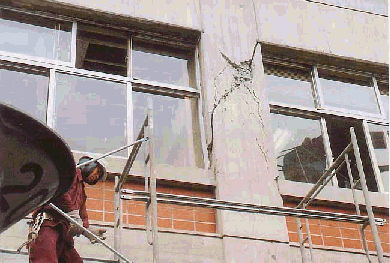 校舎の壁にひびが入り外から復旧作業をしている写真