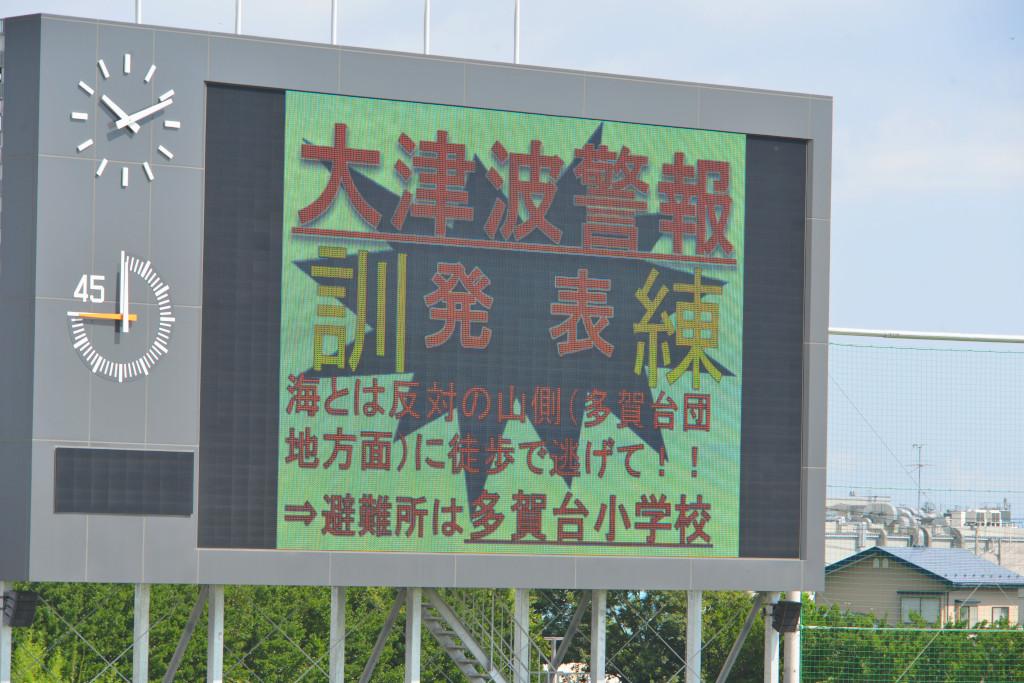 大津波警報発表と表示された競技場の電光掲示板の写真