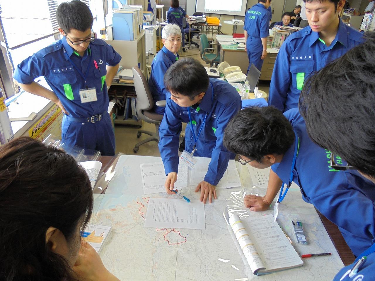 5名ほどの青の制服を着用した職員が災害図上訓練を行っている写真