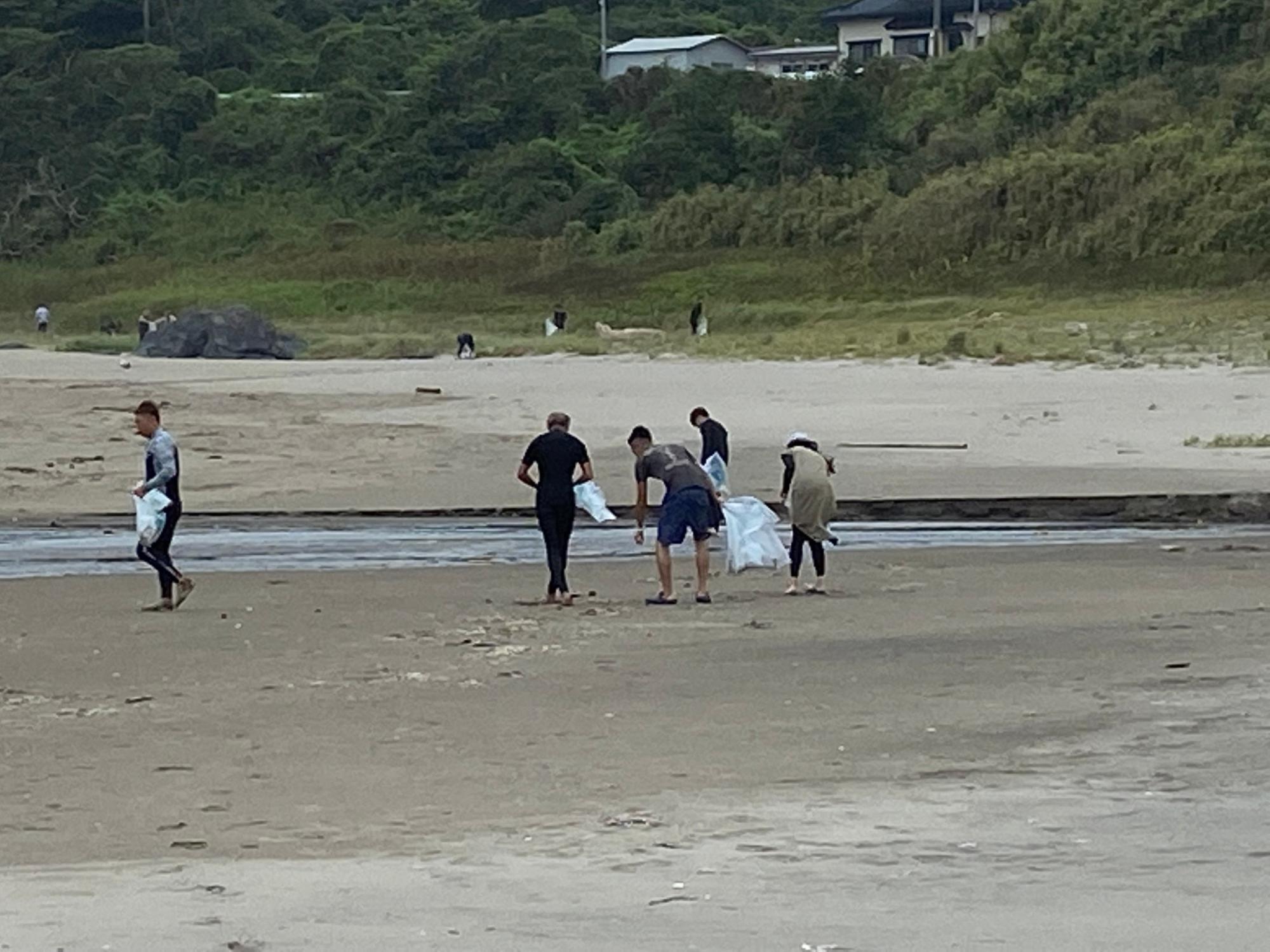 砂浜のごみを拾うサーファーの人たち