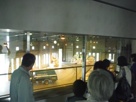 窓越しに一台のごみ収集車があるプラットホームを見学している参加者たちの写真