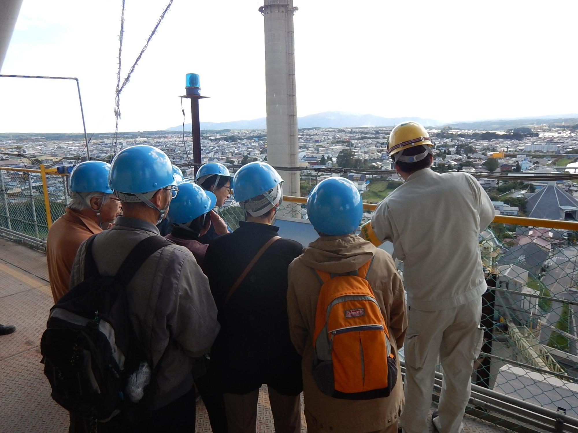 八戸セメントの建物からひときわ目立つ背の高い塔を見ているエコツアー参加者の写真