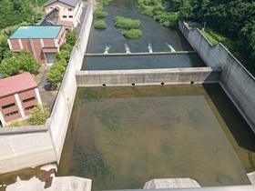 左側に水力発電所建屋が建ち、真ん中に水のたまった排出口の写真