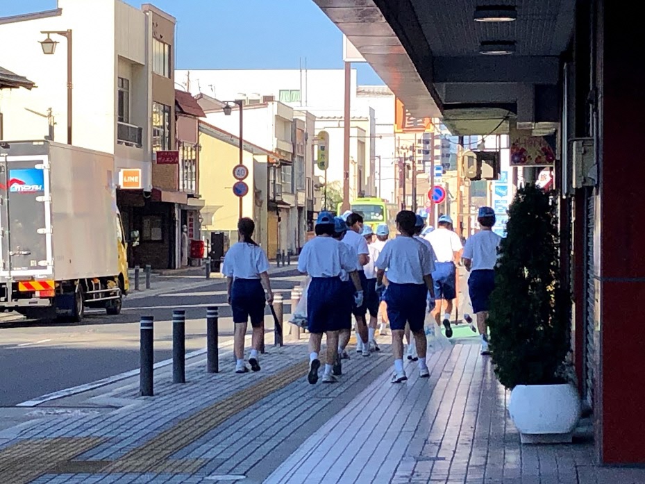 中心街の歩道のごみを拾う生徒たち