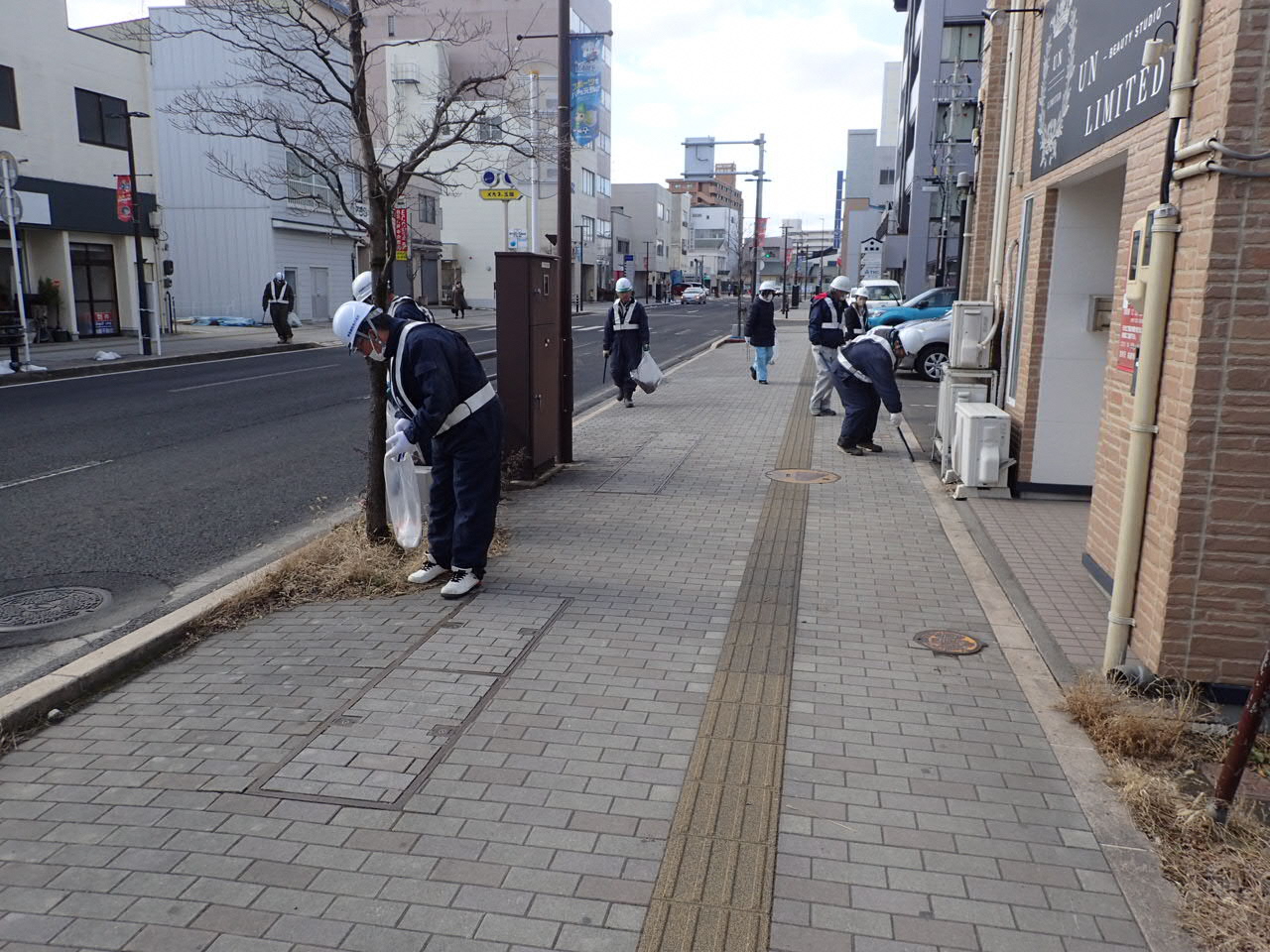 作業服姿で歩道のごみを拾っている写真